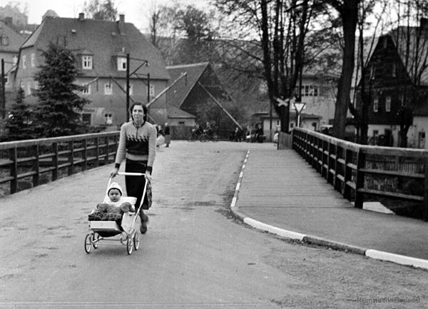 Frau mit Kinderwagen auf der Brücke.